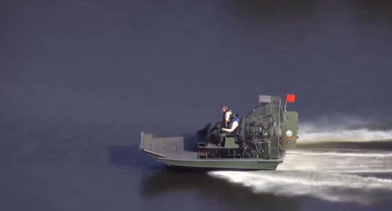 Airboat on water with two people on board.