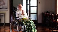Elderly woman in a wheelchair, praying.