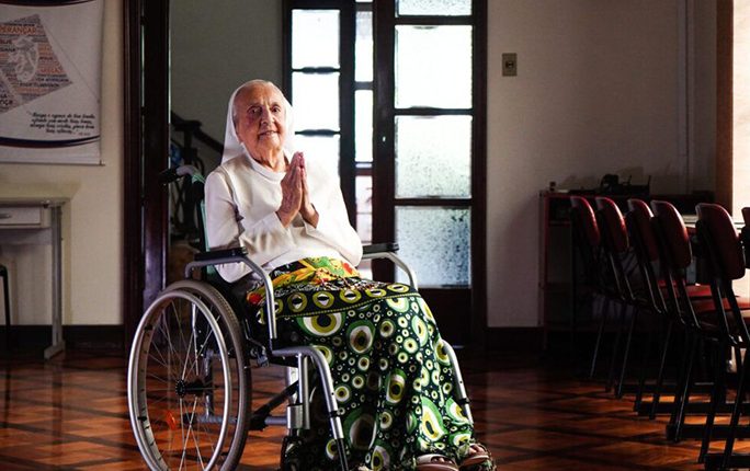 Elderly woman in a wheelchair, praying.