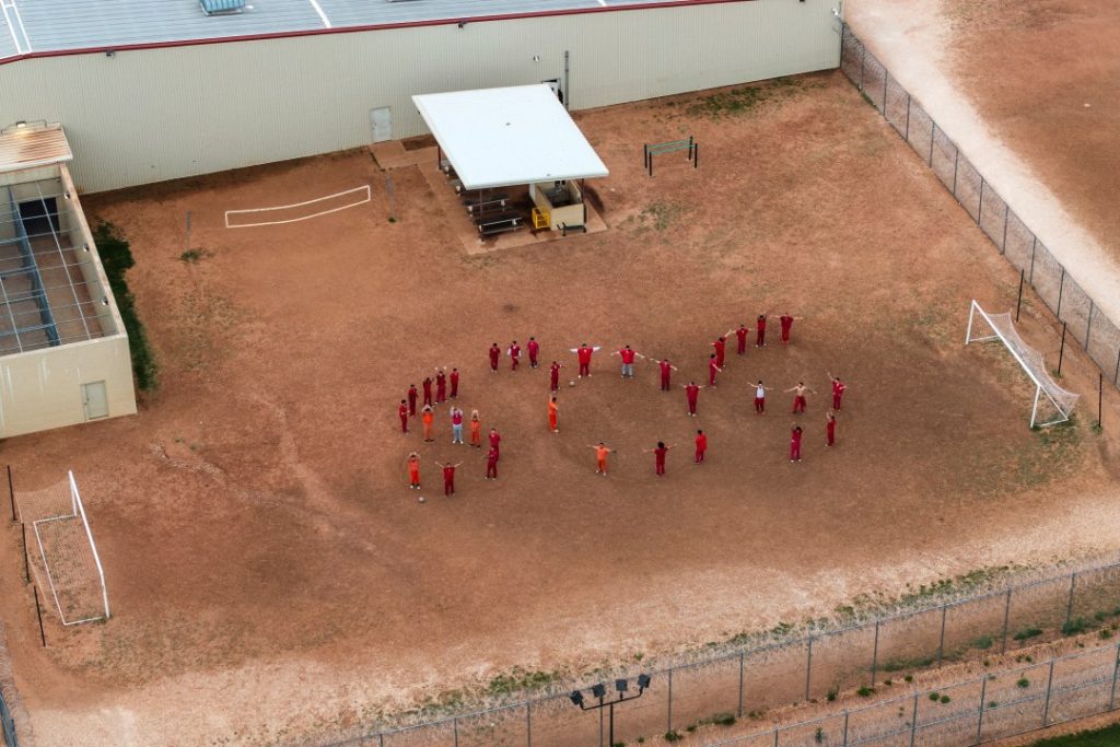 People spell out SOS with their bodies in the courtyard of a detention center