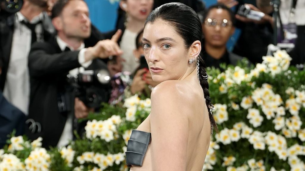 Lorde risks a major wardrobe malfunction in a revealing stuck-on bandeau top at the Met Gala amid a sea of suits