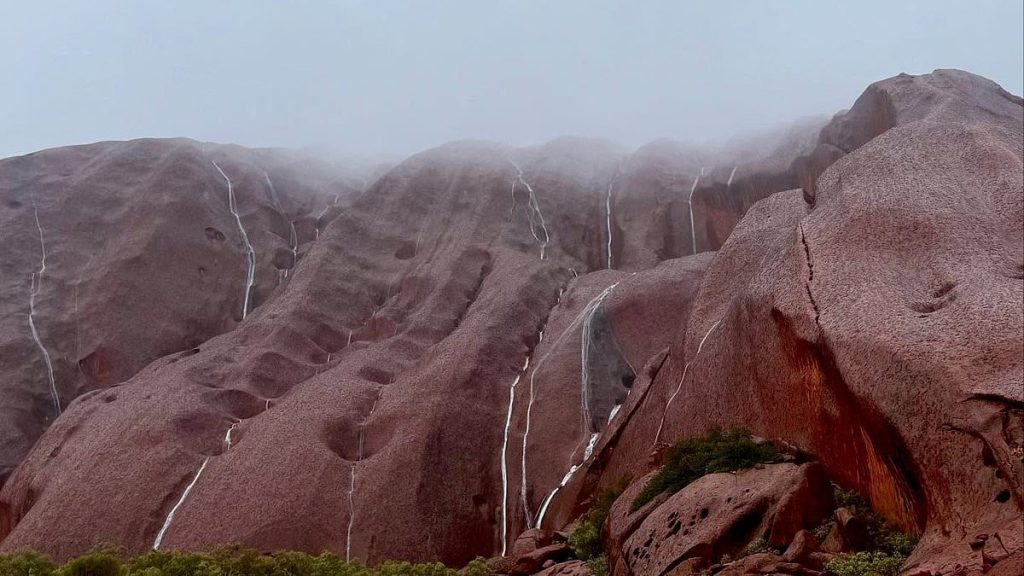 Stunning photos capture the rare moment water cascades down the sides of Uluru as mega rain bomb strikes Australia