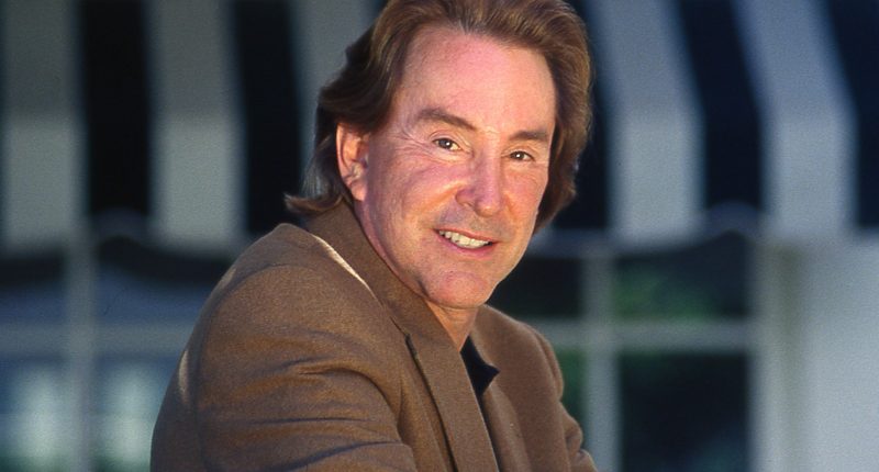 Ty Warner smiles in a brown suit jacket.