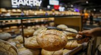Woman reaching for bread on shelves in a bakery.