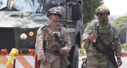 A U.S Marine, left, and a member of the California National Guard work a checkpoint together outside of a federal building, Friday, June 13, 2025, in Los Angeles (AP Photo/Damian Dovarganes)