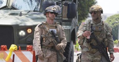A U.S Marine, left, and a member of the California National Guard work a checkpoint together outside of a federal building, Friday, June 13, 2025, in Los Angeles (AP Photo/Damian Dovarganes)