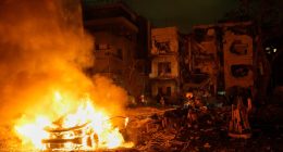 Firefighters and rescue personnel at the site of a fire following a missile attack.