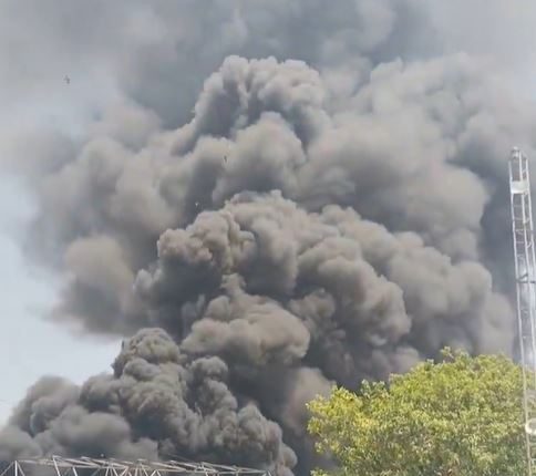 Large plume of black smoke billowing over buildings.
