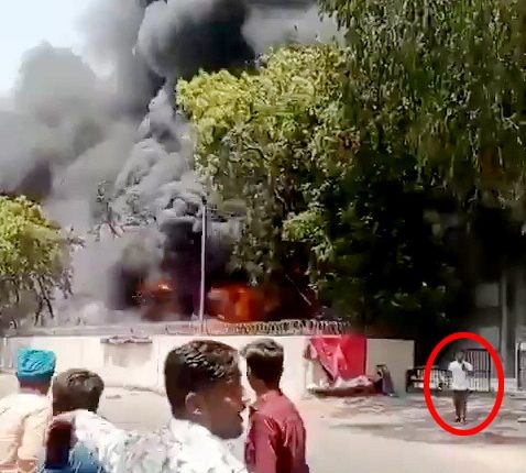 Footage of a man calmly walking away from a large fire.
