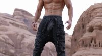 Muscular man standing on a rock.