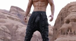 Muscular man standing on a rock.
