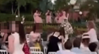People seated at white chairs outdoors watching a performance.