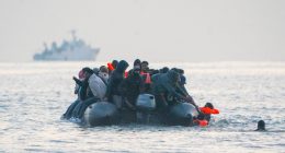 Migrants in an inflatable boat at sea.