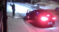 Nighttime security footage of a person near a car.
