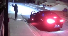 Nighttime security footage of a person near a car.