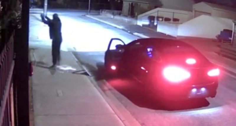 Nighttime security footage of a person near a car.