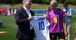 Keir Starmer presents an England football jersey to a member of the Lionesses.