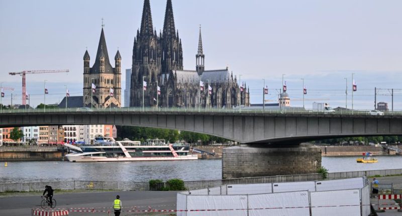 Cologne Cathedral and a bridge over the Rhine River, with a security perimeter in the foreground.