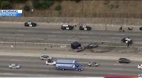 Aerial view of a freeway crash scene with multiple police vehicles and emergency personnel.
