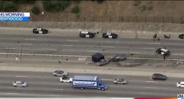 Aerial view of a freeway crash scene with multiple police vehicles and emergency personnel.