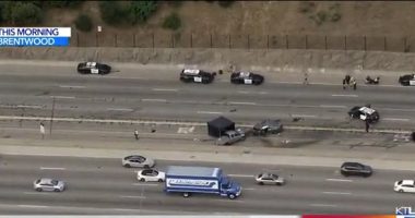 Aerial view of a freeway crash scene with multiple police vehicles and emergency personnel.