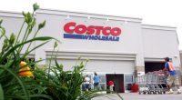 Costco Wholesale store exterior with shoppers and an employee pushing shopping carts.