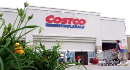Costco Wholesale store exterior with shoppers and an employee pushing shopping carts.