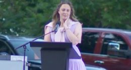 Woman crying while speaking at a podium.