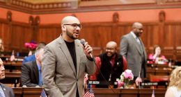 State Rep. Raghib Allie-Brennan speaking at a podium.
