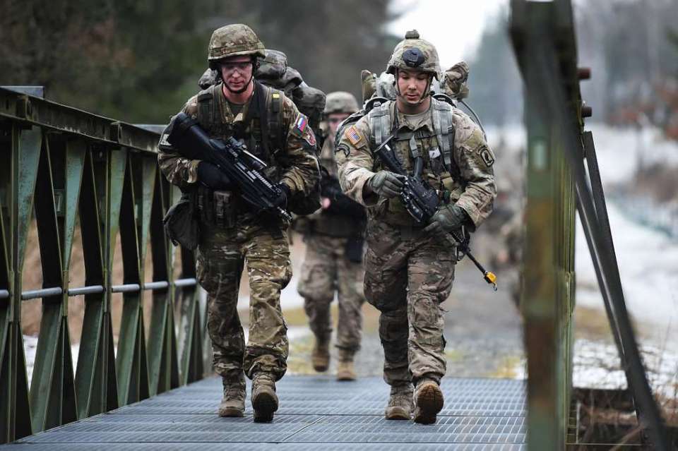 US Army paratroopers crossing a bridge.
