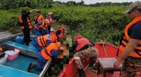 Rescue workers retrieving a body from a river.