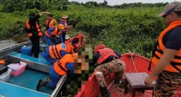 Rescue workers retrieving a body from a river.