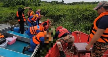 Rescue workers retrieving a body from a river.