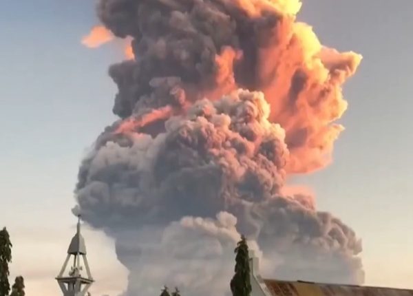 Volcanic eruption plume over a church.