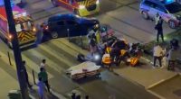Aerial view of a car accident scene with emergency responders and bystanders.