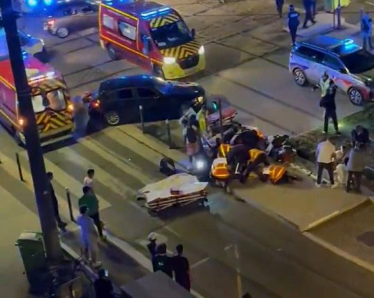 Aerial view of a car accident scene with emergency responders and bystanders.