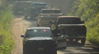 Law enforcement vehicles passing a roadblock.