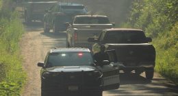 Law enforcement vehicles passing a roadblock.