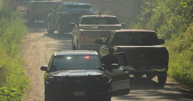 Law enforcement vehicles passing a roadblock.