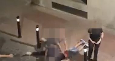 A man being restrained on the ground by another man.