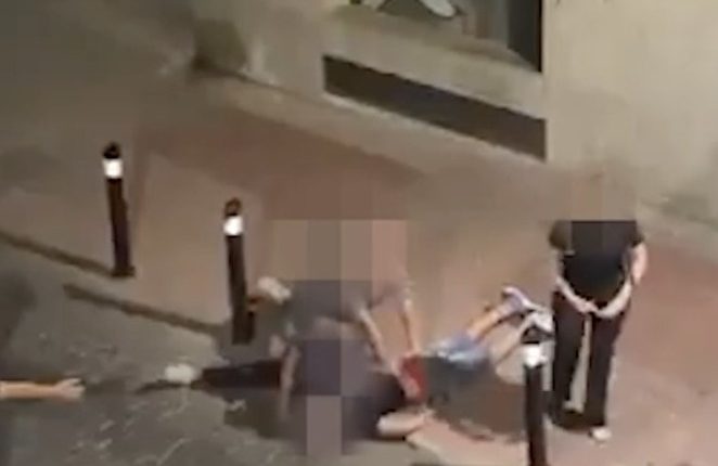 A man being restrained on the ground by another man.