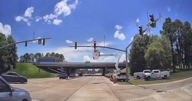 Road crews working on traffic signals at an intersection.