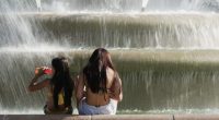 Kids cool off in the mist from a fountain as temperatures approach 100 degrees, Friday, June 20, 2025, in Kansas City, Mo. (AP Photo/Charlie Riedel)