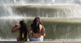 Kids cool off in the mist from a fountain as temperatures approach 100 degrees, Friday, June 20, 2025, in Kansas City, Mo. (AP Photo/Charlie Riedel)