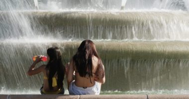Kids cool off in the mist from a fountain as temperatures approach 100 degrees, Friday, June 20, 2025, in Kansas City, Mo. (AP Photo/Charlie Riedel)