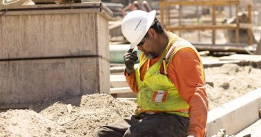 A construction worker sits and puts his head down, still in the hot sun.