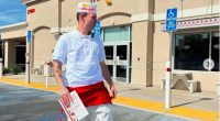 Man in In-N-Out Burger uniform outside restaurant.