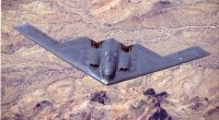 B-2 Spirit stealth bomber in flight over desert terrain.
