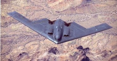 B-2 Spirit stealth bomber in flight over desert terrain.