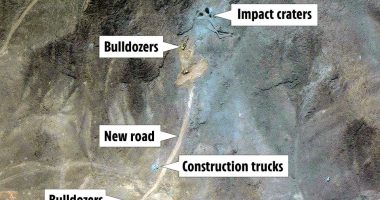 Aerial view of construction activity showing bulldozers, construction trucks, a new road, and impact craters.